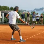 Tennista maturo colpisce un dritto su un campo in terra rossa, con alcuni spettatori dietro la recinzione e il mare sullo