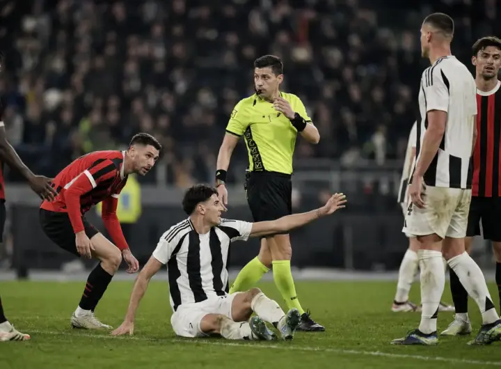 Arbitro in maglia gialla valuta un contatto in area mentre un giocatore bianconero è a terra e protesta