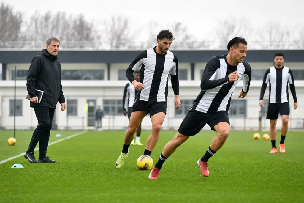 Allenamento di calcio: due attaccanti in maglia bianconera durante un esercizio, con un allenatore a bordo campo