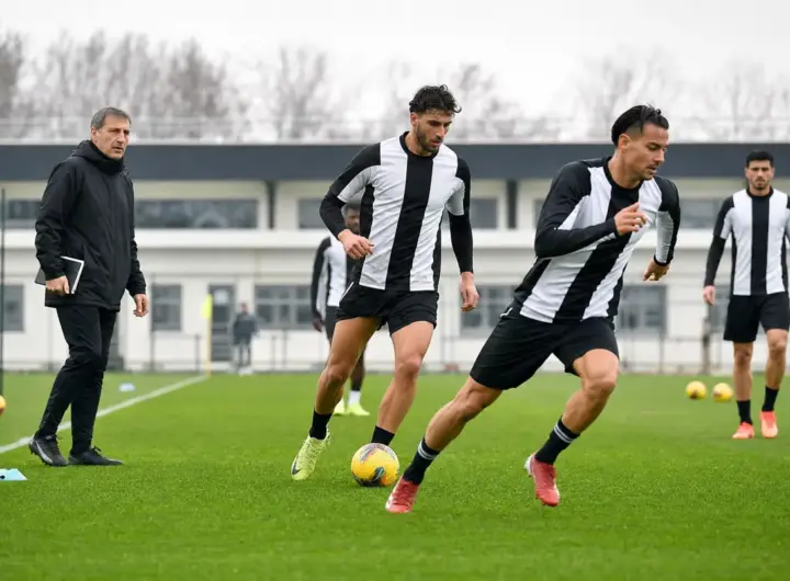 Allenamento di calcio: due attaccanti in maglia bianconera durante un esercizio, con un allenatore a bordo campo